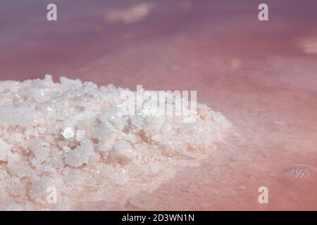 Salt pink crystals bunch close-up shining in pink water surface with mirror reflection. Spa travel recreation on Syvash or Sivash, Rotten Sea, Ukraine Stock Photo