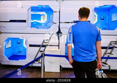 A man stands in front of a capsule hotel for travelers. Capsule hotel open entrance hole with inside interior - Sheremetievo airport, Moscow / Russia Stock Photo