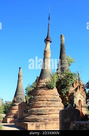 Ruins of old stone pagodas with green plants growing on them at In Dien located on the southwestern side of Inle Lake, Myanmar Stock Photo