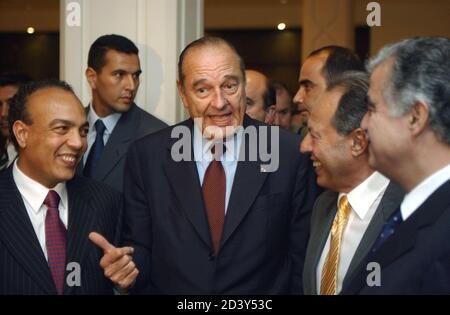 French President Jacques Chirac (2nd L) poses with Mohamed Chelali (L), Lebanese President Emile Lahoud and Prime Minister Rafic Hariri (R) talk together after a visit to UNESCO's offices October 17, 2002. [Chelali saved Chirac's life after preventing a gunman from shooting him while he reviewed troops on July 14, 2002, France's National Day. Chirac is in Lebanon ahead of a summit of French-speaking nations taking place in Beirut on October 18-20.]