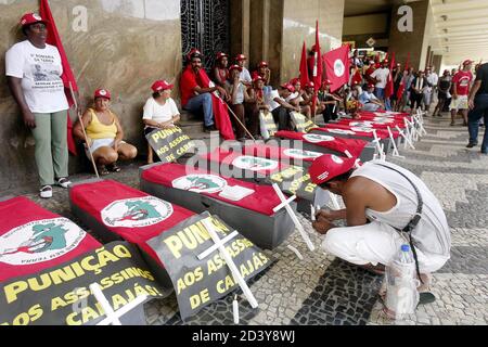A member of Brazil's Landless Movement (MST) lights a candle next to coffins during a demonstration in Rio de Janeiro April 16, 2004, marking the eighth anniversary of a police massacre of 19 rural workers. Landless workers, trade unions and Roman Catholic Church groups have called for a day of protests to remember those killed in the 1996 massacre in which police opened fire on farmers demanding land in the remote in Eldorado dos Carajas, Northeastern Brazil. REUTERS/Sergio Moraes  SM/HB