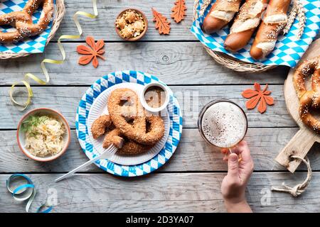 Celebrating Oktoberfest alone. Traditional food and beer, top view on wooden table outdoors, Stock Photo