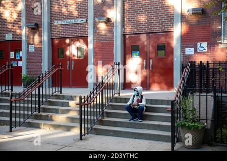 (201008) -- NEW YORK, Oct. 8, 2020 (Xinhua) -- A student is seen on the steps of the closed public school PS 139 in the Ditmas Park neighborhood in Brooklyn of New York, the United States, Oct. 8, 2020. The latest coronavirus positivity rate in the 20 hotspot ZIP codes in Queens, Brooklyn, Orange and Rockland counties in New York State was 5.8 percent, more than five times the statewide positivity rate excluding these ZIP codes which stood at 1.01 percent, tweeted Governor Andrew Cuomo on Thursday. Shutdowns of non-essential businesses, schools and social gatherings in those hotspot areas have Stock Photo