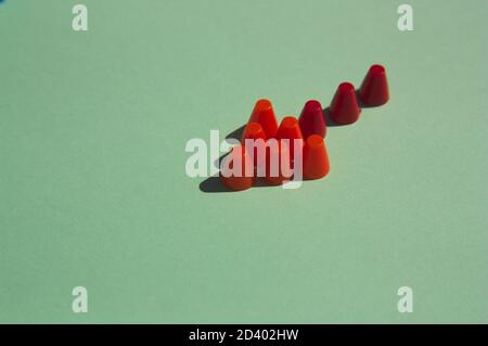An arrow made up of multi-colored pivots on a flat green surface with copy space Stock Photo