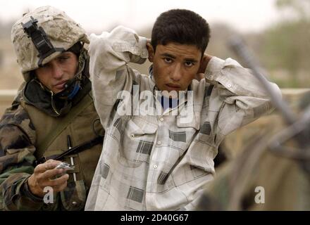 A U.S. Marine from Lima Company, a part of the 7th Marine Regiment, searches a member of the Iraqi Republican guard dressed in civilian clothes for weapons on the New Baghdad highway bridge in the suburbs of the Iraqi capital Baghdad on April 7, 2003.  [U.S. forces burst into the heart of Baghdad on Monday and entered two palace complexes of President Saddam Hussein, but they said the operation was an armoured raid not intended to hold territory.]