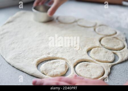 Preparation of the dough for baking, freezing, sculpting and other food blanks - a large piece of the dough is on the table the chef cuts out small Stock Photo