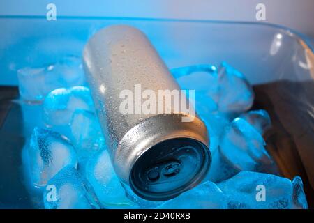 Water drops on surface of silver can lying on blue ice cubes without people in Mexico Stock Photo