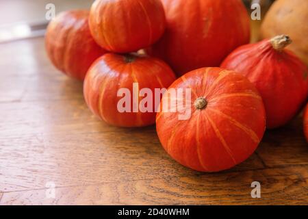 Flat lay of the small, red hokkaido pumpkins lie on the wooden floor. Halloween decorations. Copy Space. Postcard for the holiday. Autumn fresh vegeta Stock Photo