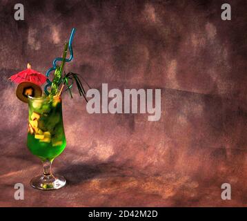 Tall glass with kiwi juice and ice, decorated with a straw and an umbrella on a gray background. Close-up. Stock Photo