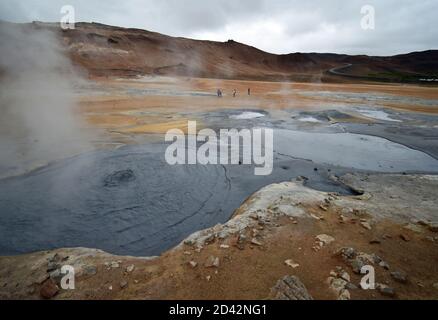 Taken from the boardwalk of the Námafjall and Hverir Viewpoint near Lake Myvatn In North Iceland. Visitors walk past the geothermal grey boiling mud. Stock Photo