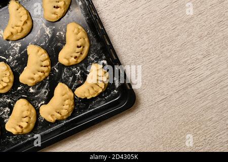 Sweet patties with a curly edge. On which they are laid out, raw, prepared for baking. Left on the table. Stock Photo