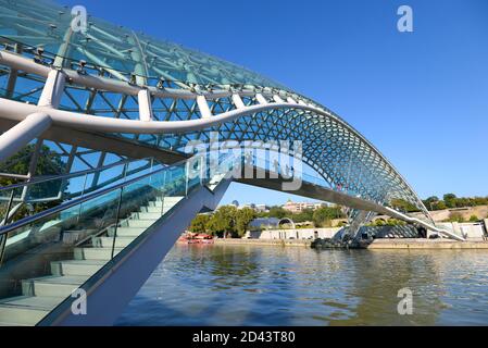 Bridge of Peace in Tbilisi, Georgia. Modern design pedestrian bridge crossing Kura River. Built of curvy steel and glass. Stock Photo