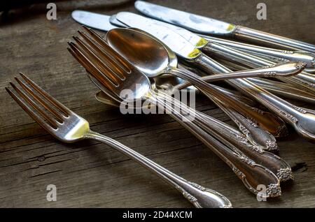 Fancy forks, knives and spoons are set out on a table, to be spread out for dinner Stock Photo