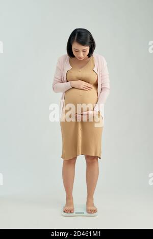 Pregnant woman standing on scales at home. Pregnancy weight gain concept Stock Photo