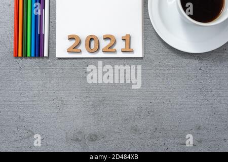 New Year 2021. Flat lay of office space with the cup of coffee, notepad, colored pencils and wooden numbers. Stock Photo