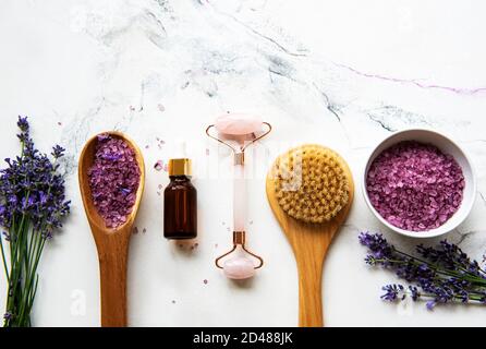 Set of natural organic SPA cosmetic with lavender. Flat lay bath salt,  essential oils, face roller,  on marble background. Skin care, beauty treatmen Stock Photo