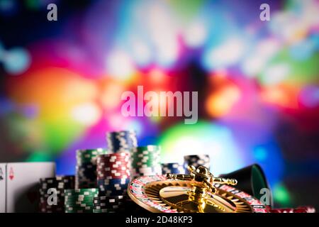 Casino concept.  Roulette wheel, poker chips and dice on shining table and on  colorful bokeh background. Stock Photo