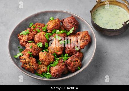 Veg Pakora in gray bowl on concrete table top. Pakoda is indian cuisine appetizer deep fried dish. Asian food and meal Stock Photo