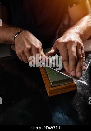 Sharpening the knife with whetstone, close up shot Stock Photo