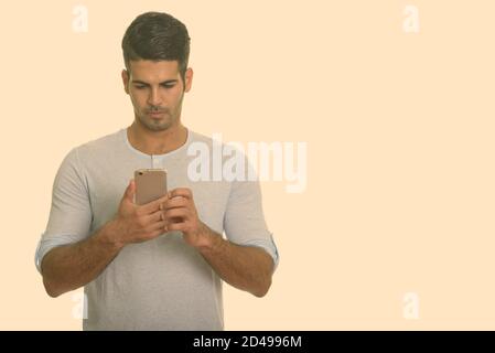 Young handsome Persian man using mobile phone Stock Photo