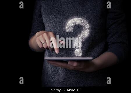 Girl's hand holds tablet with virtual hologram question mark Stock Photo