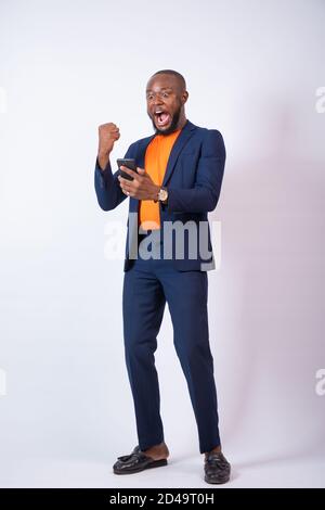 young african businessman looking at his phone looks very surprised and celebrates Stock Photo