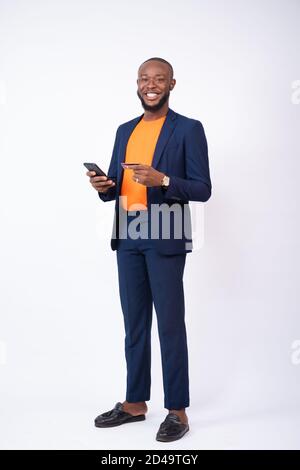 african businessman using his phone and credit card smiling, standing against a white background Stock Photo