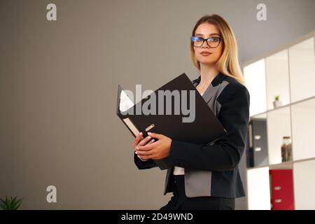 blonde in the office and jacket holding documents Stock Photo