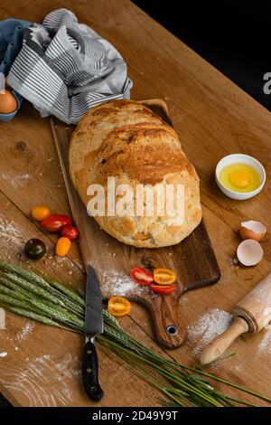 Bakery - gold rustic crusty loaves of bread. Still life captured from above (top view, flat lay).  Fresh bread placed on a towel together with tomatoe Stock Photo