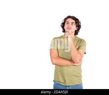 Portrait of pensive young man, long curly hair style, keeps hand under chin, thoughtful gesture, isolated over white background with copy space. Casua Stock Photo