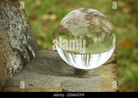 Autumn forest seen through a lens ball. Glass ball in a forest with blurry view and reflections. Stock Photo