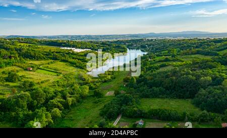 Aerial view over lake next to the colorful forest on hilly landscape, treetops Stock Photo