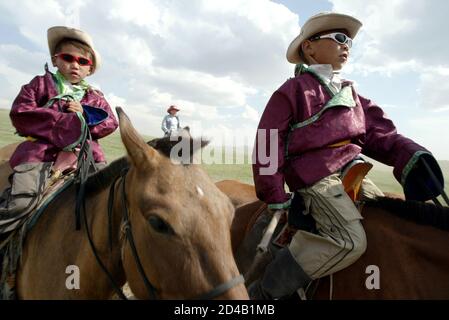 Two young Mongolian riders mount their horses at Khui Doloon Khudag village, some 35 km (21 miles) from the capital Ulan Bator July 10, 2003 on the eve of the Naadam Festival. Naadam is the biggest event on the Mongolian calendar held from July 11 to 13, on the anniversary of the Mongolian revolution of 1921. [Concerts, fairs and traditional sports like wrestling, archery and horse racing are held during the celebration.]