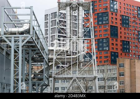 The exterior of the boiler room with the output of shiny metal pipes against the background of a number of residential buildings. Stock Photo