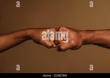 Cropped shot of two hands doing a fist bump. Two fists touching each other in opposite direction. Stock Photo