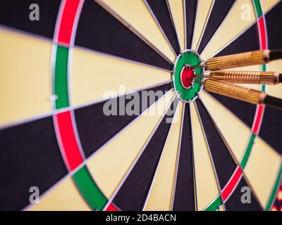 A closeup shot of three darts in the bullseye of a dart board Stock Photo