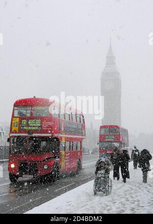London buses cross Westminster Bridge in driving snow in London, January 8, 2003. Snow and freezing conditions continued to cause travel disruption across the UK on Wednesday. REUTERS/Jonathan Bainbridge  ASA