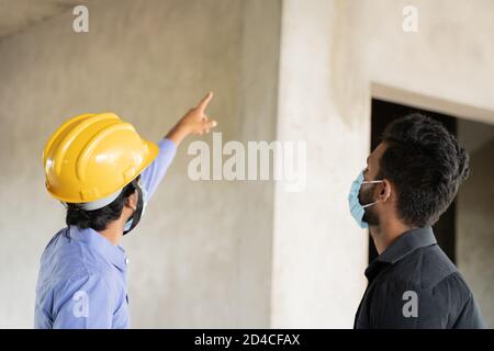 selective focus on hardhad, Two construction worker in medical mask busy in work while maintaining social distancing - concept of covid-19 or Stock Photo