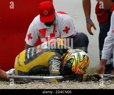 Italy's 250cc rider Dovizioso helped by medical staff after crash during free practice for Catalan Motorcycle Grand Prix.  Italy's 250cc rider Andrea Dovizioso is helped by medical staff after a crash during free practice for the Catalan Motorcycle Grand Prix at Circuit de Catalunya race track near Barcelona June 11, 2005. Dovizioso came off the track on one of the Montmelo circuit's famously fast corners and slid across the gravel trap with his bike before thumping back-first into the tyre wall. REUTERS/Albert Gea