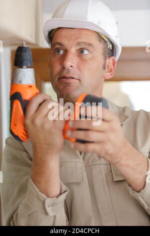 mature male builder using cordless screwdriver Stock Photo