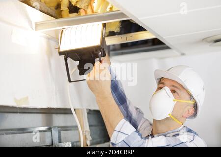 plasterer wearing dust mask while checking the ceiling Stock Photo