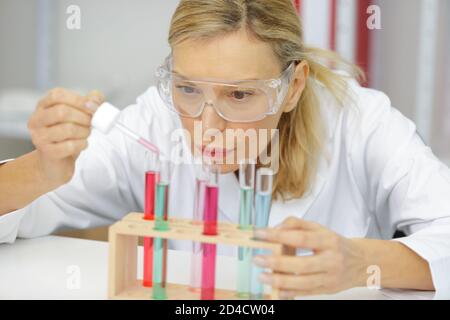 mature female researcher using a pipette in lab Stock Photo