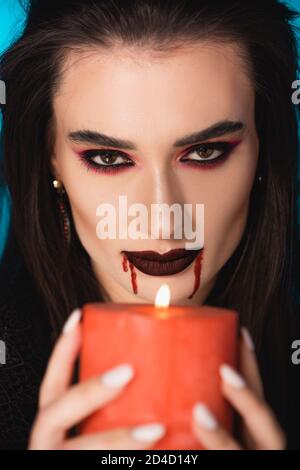selective focus of woman with blood on face holding burning candle Stock Photo