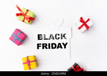 Top view of paper element with black friday lettering near toy shopping bags on white background Stock Photo