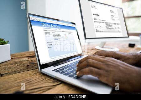 Young Businessman Looking At Invoice While Doing Online Banking On Computer Stock Photo