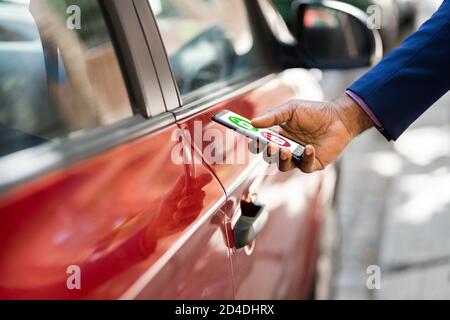 African Man Unlocking Car Using Smartphone App Stock Photo