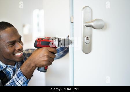 African Locksmith Man Changing And Fixing Door Lock Stock Photo