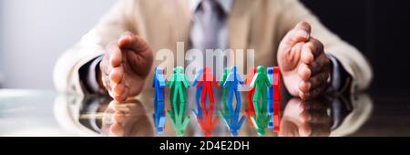 African Man Protecting Employee Figures With Hand Stock Photo