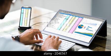 Analyst Employee Using Spreadsheet Software On Phone With External Screen Stock Photo