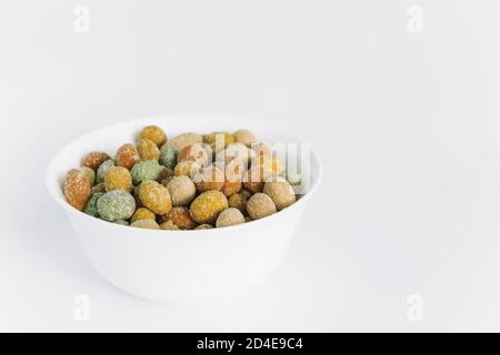Salted peanuts covered with glaze in a ceramic bowl on a white background. A snack on the way. Delicious appetizer. Close up. Copy space. Stock Photo